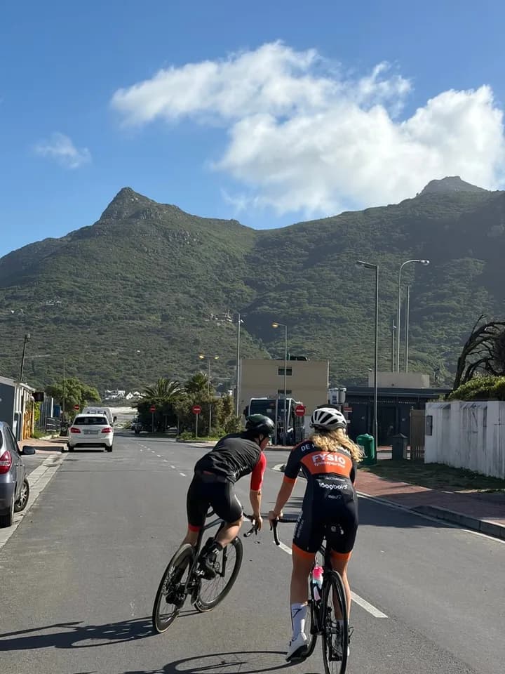 Sterre on her road bike with a riding buddy, a mountain in the background